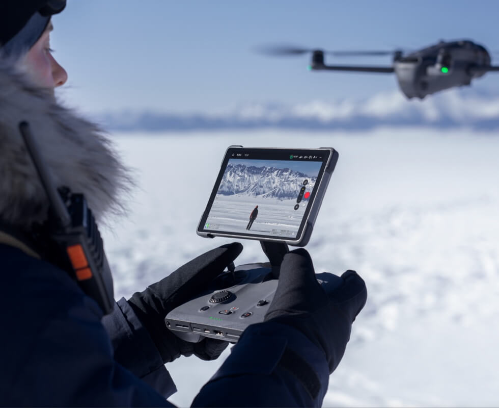 DJI Mavic 4 Pro Pilot mit Controller in Schneelandschaft